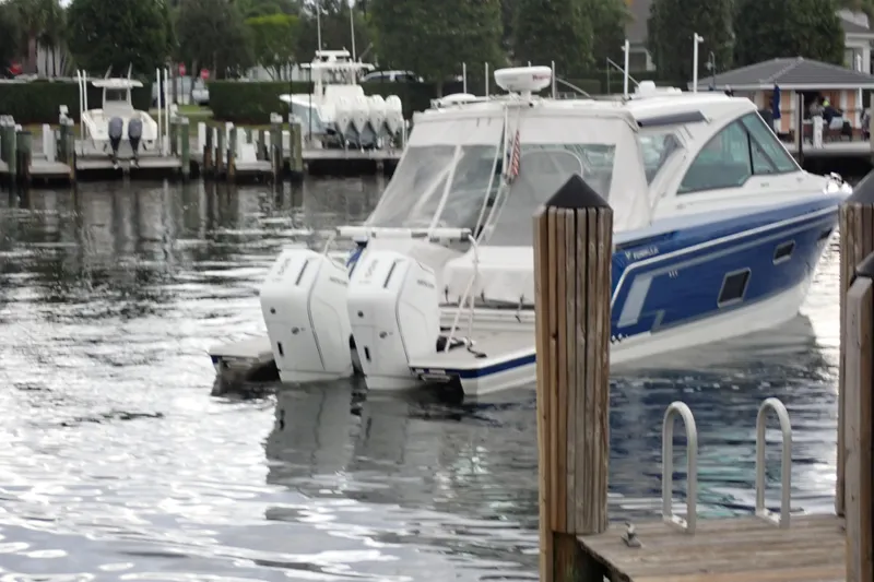 Slide: The Image of 2023 Formula 380 Super Sport Crossover OB docked at marina, featuring dual outboard engines. - 6