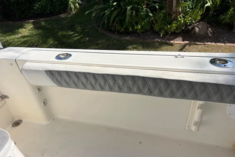 Slide: The Image of 1999 Pursuit 2470 Walkaround boat interior with cushioned seating and rod holders. - 15