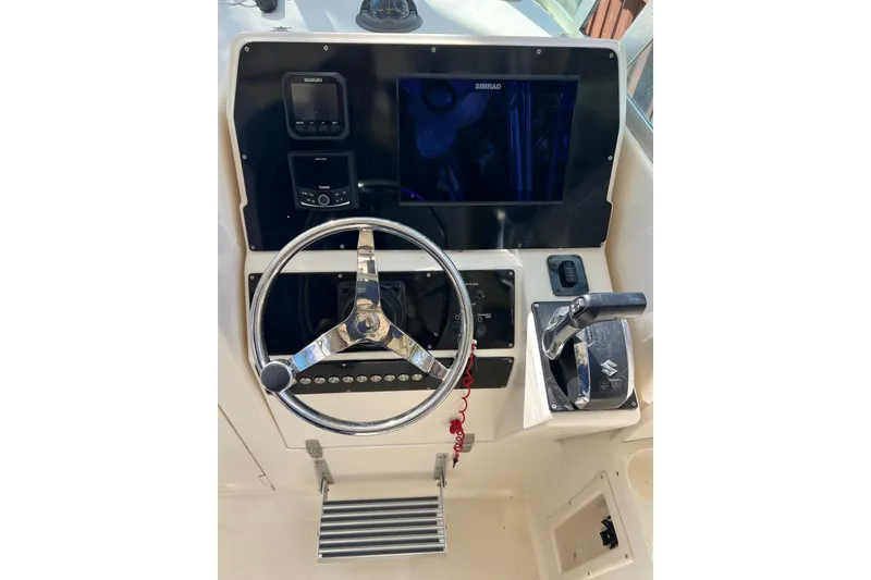 Slide: The Image of 1999 Pursuit 2470 Walkaround boat dashboard with steering wheel and controls. - 20