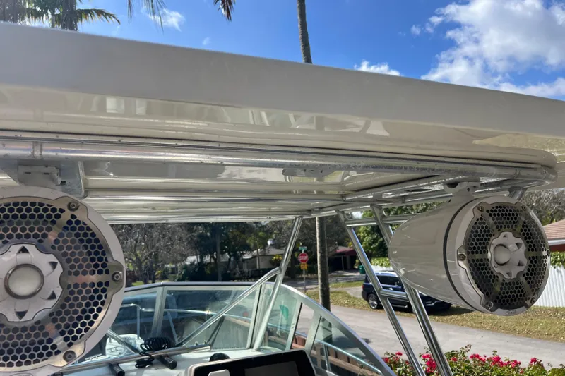 Slide: The Image of 1999 Pursuit 2470 Walkaround boat speakers and canopy under clear blue sky. - 23