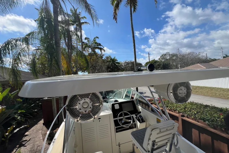 Slide: The Image of 1999 Pursuit 2470 Walkaround boat with speakers, steering wheel, and palm trees in the background. - 24