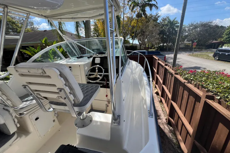Slide: The Image of 1999 Pursuit 2470 Walkaround boat with helm, seating, and outdoor view. - 28
