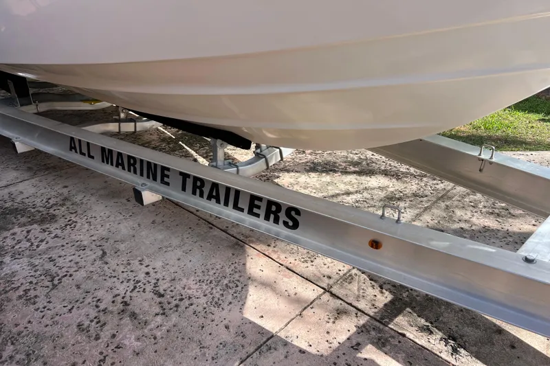 Slide: The Image of 1999 Pursuit 2470 Walkaround boat on All Marine Trailers, parked on concrete. - 8