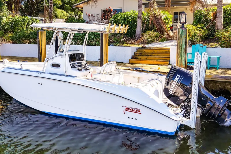 Slide: The Image of 2004 Boston Whaler 240 Outrage boat docked with Suzuki outboard motor. - 2