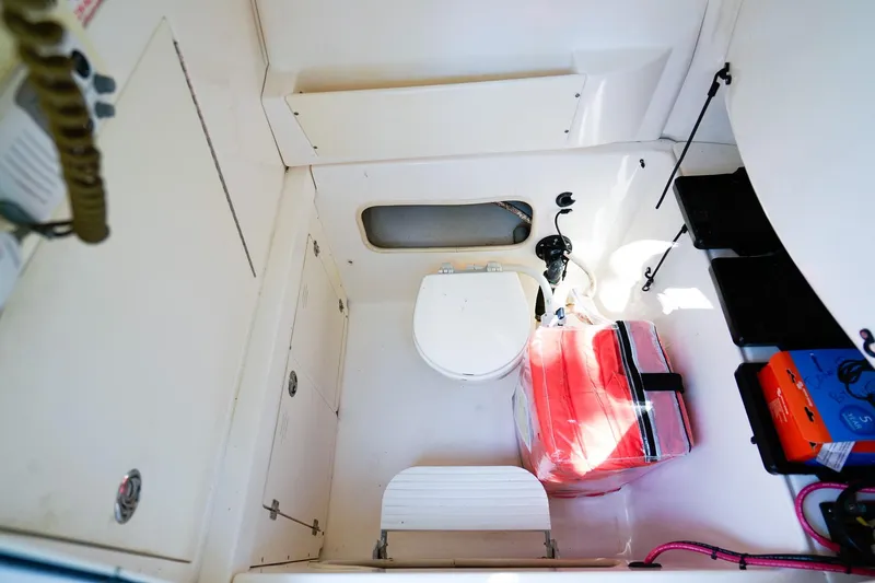 Slide: The Image of 2004 Boston Whaler 240 Outrage interior with storage, toilet, and equipment. - 20