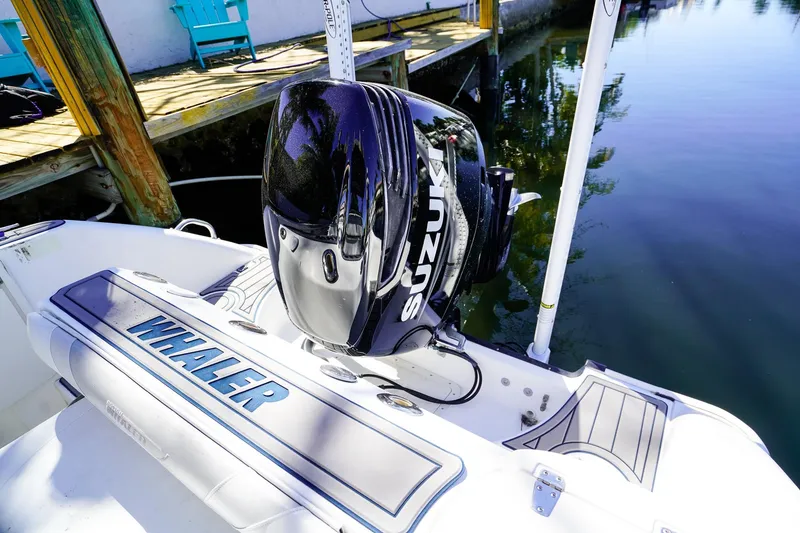 Slide: The Image of 2004 Boston Whaler 240 Outrage with Suzuki outboard motor docked by water. - 6