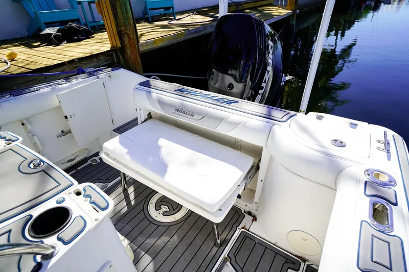 Slide: The Image of 2004 Boston Whaler 240 Outrage boat interior with seating and motor, docked by water. - 9