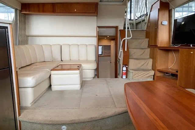 Slide: The Image of 1998 Silverton 372 Motor Yacht interior with beige seating, wooden accents, and staircase. - 45