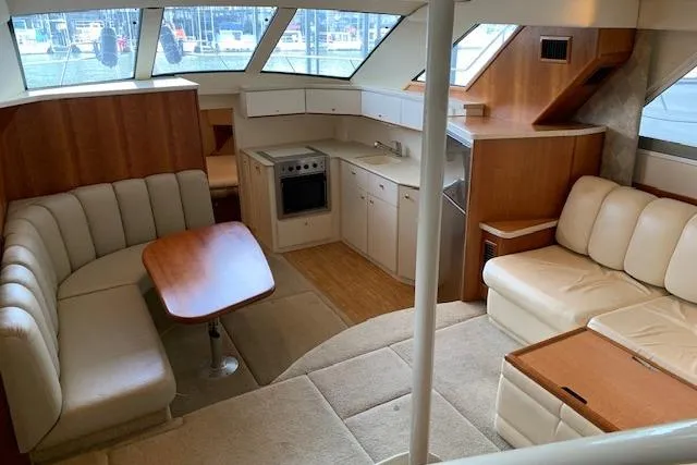 Slide: The Image of 1998 Silverton 372 Motor Yacht interior with beige seating and compact kitchen area. - 49