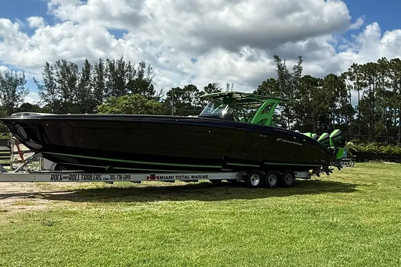 Slide: The Image of 2020 Midnight Express Open 43 boat on trailer, parked on grass under cloudy sky. - 16