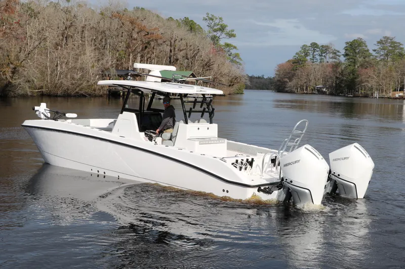 Slide: The Image of 2024 Twin Vee 280 GFX CC boat cruising on a calm river with twin Mercury engines. - 0