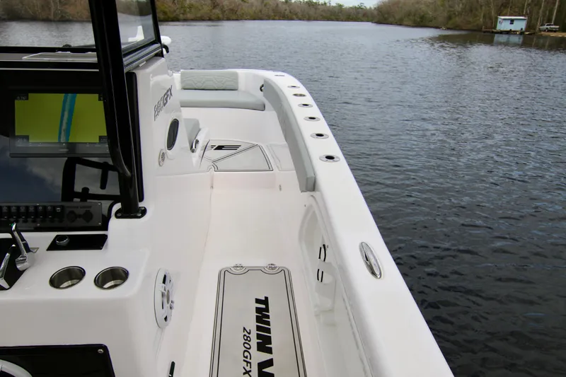 Slide: The Image of 2024 Twin Vee 280 GFX CC boat interior with console and seating on calm water. - 14