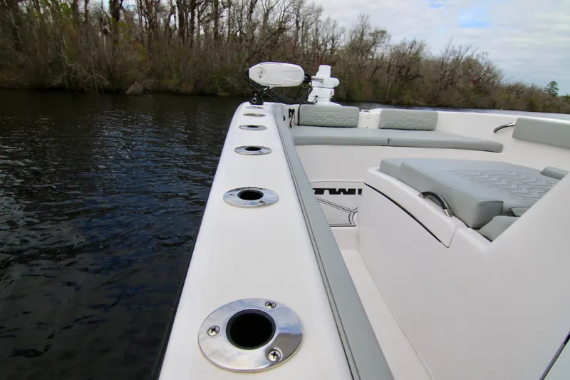 Slide: The Image of 2024 Twin Vee 280 GFX CC boat interior with rod holders, on a calm river. - 17