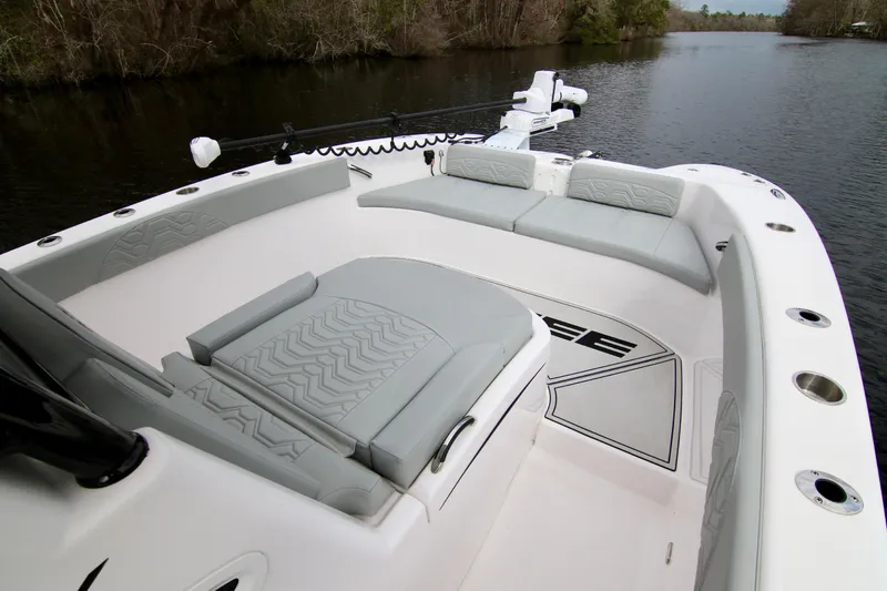 Slide: The Image of 2024 Twin Vee 280 GFX CC boat interior with cushioned seating on a calm river. - 18