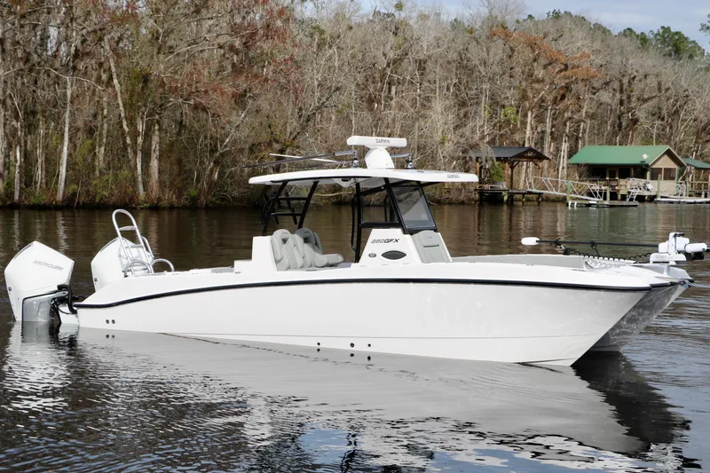 Slide: The Image of 2024 Twin Vee 280 GFX CC boat on a calm river with wooded background. - 2