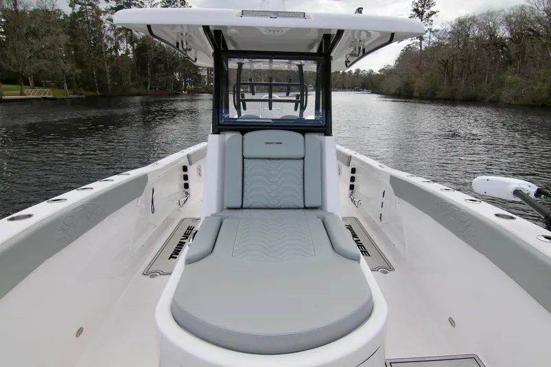 Slide: The Image of 2024 Twin Vee 280 GFX CC boat on a serene river, showcasing sleek design and comfort. - 21