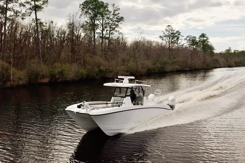 Slide: The Image of 2024 Twin Vee 280 GFX CC cruising on a scenic river with forested banks. - 8