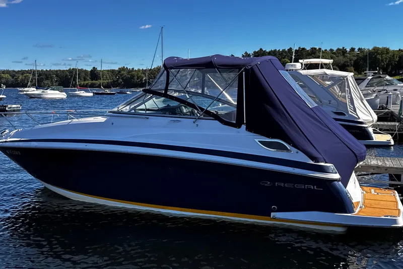 Slide: The Image of 2014 Regal 28 Express boat docked in a marina, featuring a sleek design and blue canopy. - 12