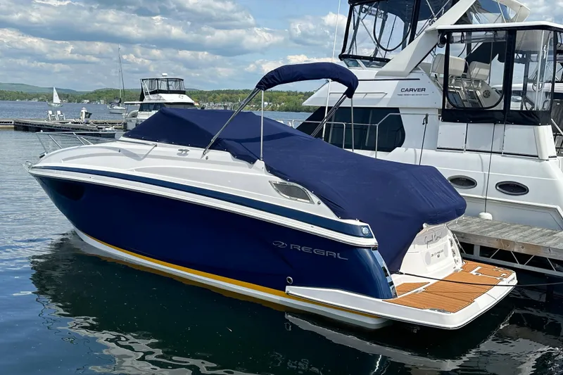 Slide: The Image of 2014 Regal 28 Express boat docked with blue cover, calm water background. - 13