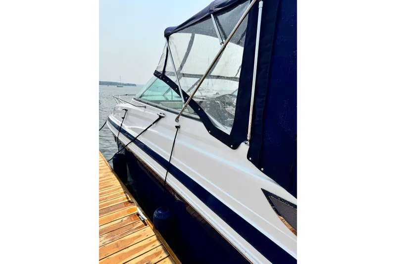 Slide: The Image of 2014 Regal 28 Express boat docked, featuring sleek design and blue canopy. - 2