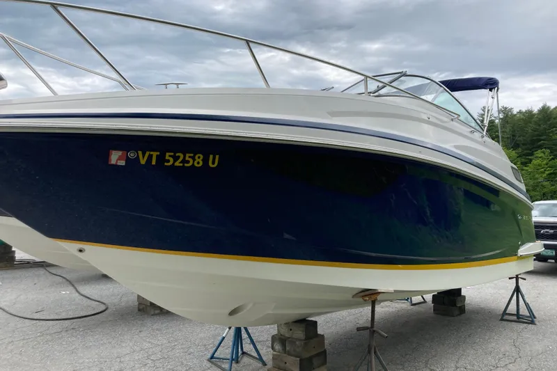 Slide: The Image of 2014 Regal 28 Express boat on stands, blue hull, overcast sky. - 20