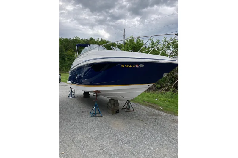 Slide: The Image of 2014 Regal 28 Express boat on stands, blue hull, overcast sky background. - 23