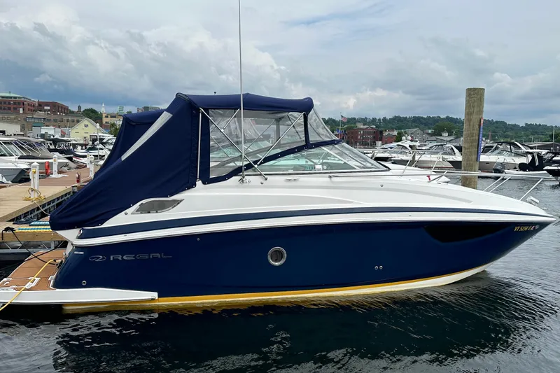 Slide: The Image of 2014 Regal 28 Express boat docked at marina, featuring sleek design and blue canopy. - 32