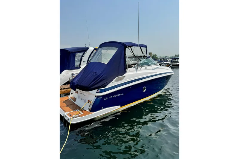 Slide: The Image of 2014 Regal 28 Express boat docked on calm water, featuring a blue and white exterior. - 4