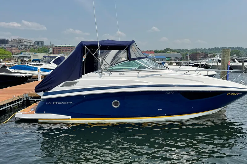 Slide: The Image of 2014 Regal 28 Express boat docked at marina, featuring sleek design and blue canopy. - 5