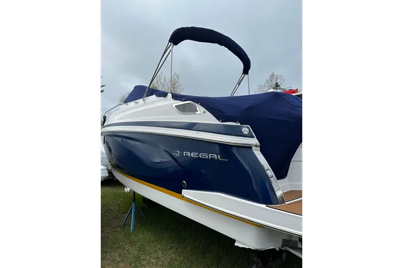 Slide: The Image of 2014 Regal 28 Express boat with blue cover, parked on grass. - 6