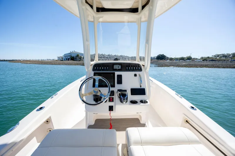 Slide: The Image of 2024 Grady-White 251 Coastal Explorer boat interior with steering wheel and controls on water. - 19