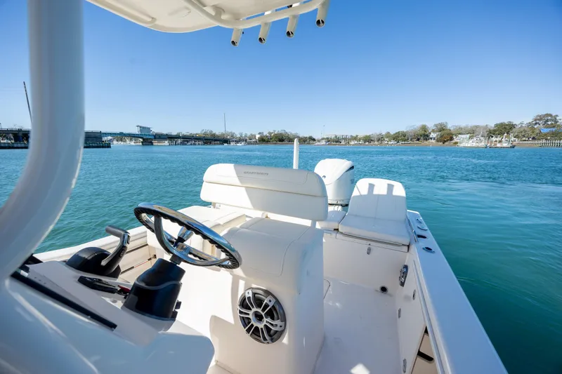 Slide: The Image of 2024 Grady-White 251 Coastal Explorer boat on serene blue water, showcasing helm and seating. - 21