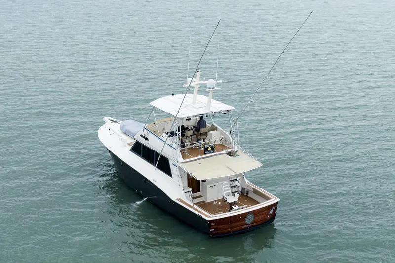 Slide: The Image of 1984 Hatteras 52 Convertible yacht on calm water, rear view with fishing rods. - 10