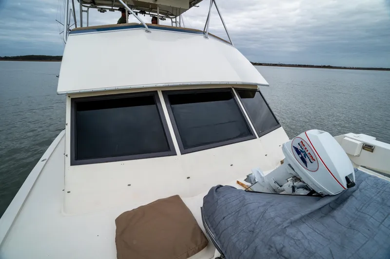 Slide: The Image of 1984 Hatteras 52 Convertible yacht on calm water, featuring a covered outboard motor. - 24