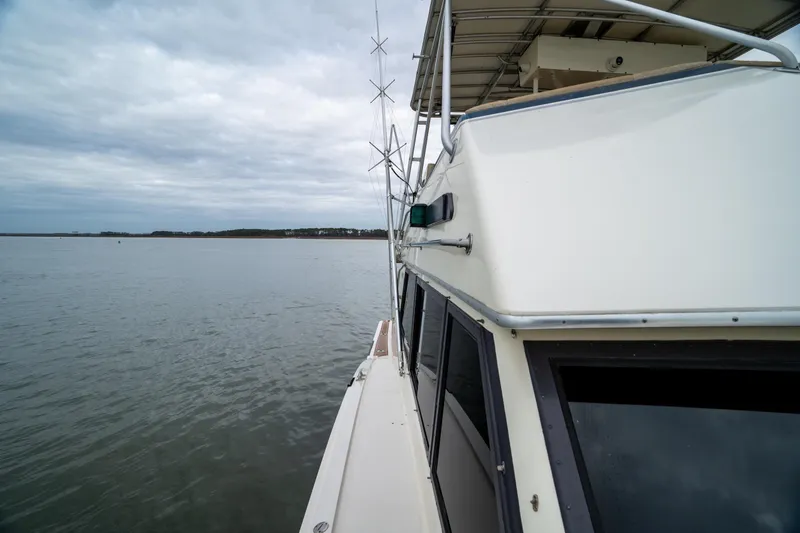 Slide: The Image of 1984 Hatteras 52 Convertible yacht on calm waters under cloudy skies. - 25