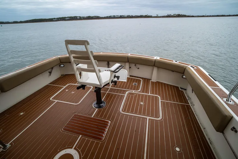 Slide: The Image of 1984 Hatteras 52 Convertible boat deck with fishing chair, overlooking calm waters. - 29