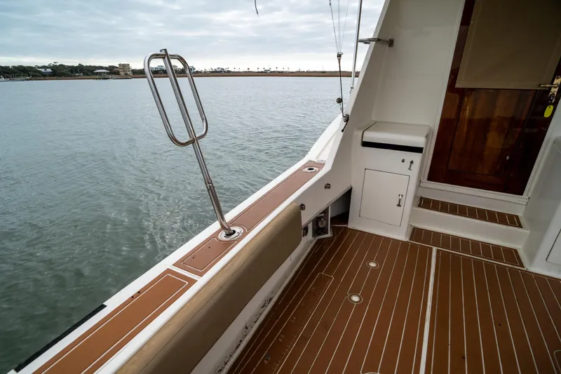 Slide: The Image of 1984 Hatteras 52 Convertible yacht deck with wooden flooring and water view. - 33