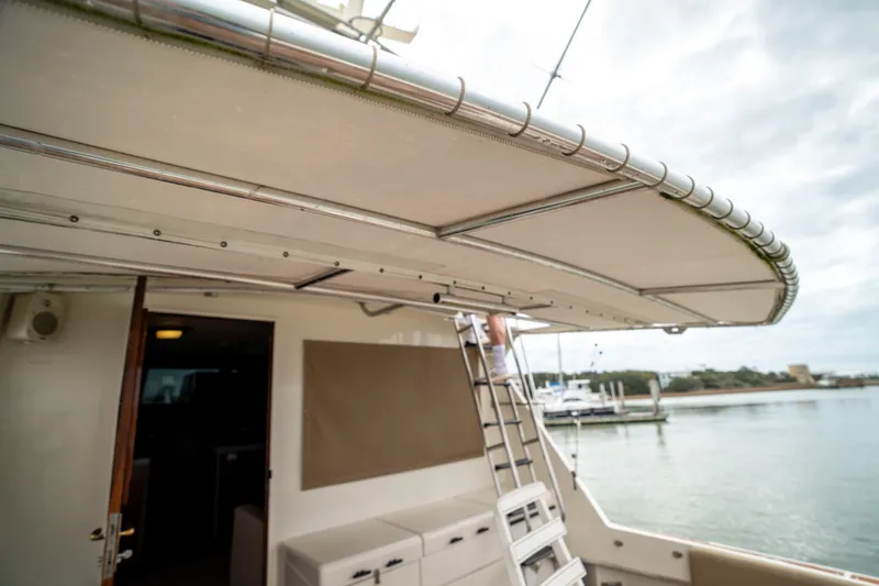 Slide: The Image of 1984 Hatteras 52 Convertible yacht with ladder and canopy, docked by the water. - 37