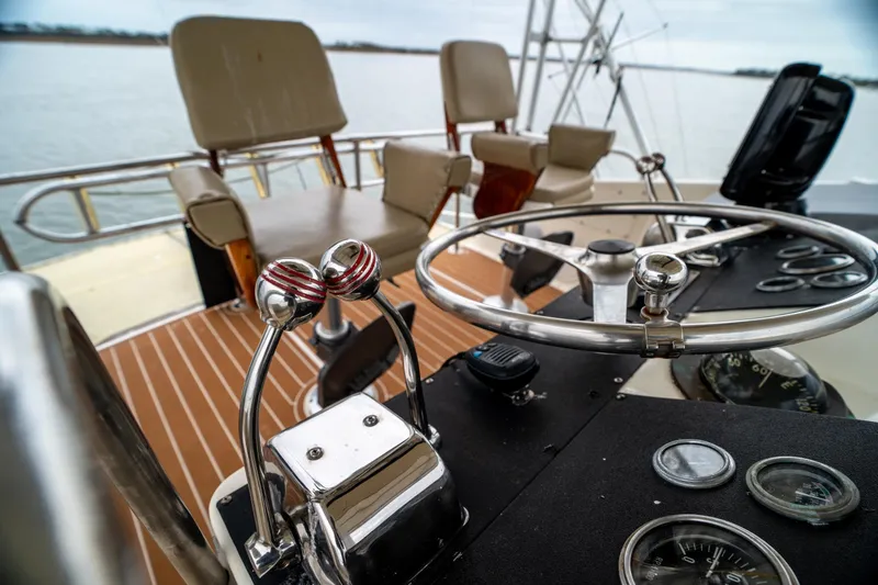 Slide: The Image of 1984 Hatteras 52 Convertible yacht helm with steering wheel and controls, on calm water. - 47