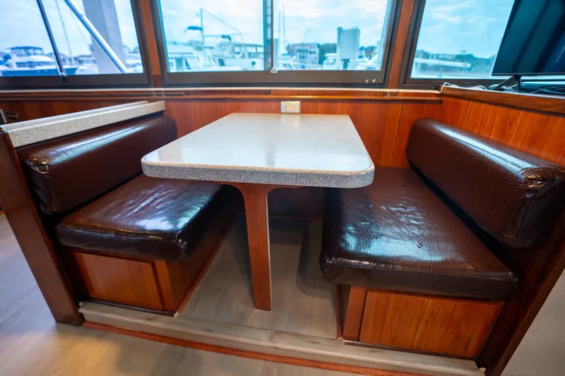 Slide: The Image of 1984 Hatteras 52 Convertible interior with brown leather seating and wooden table. - 68