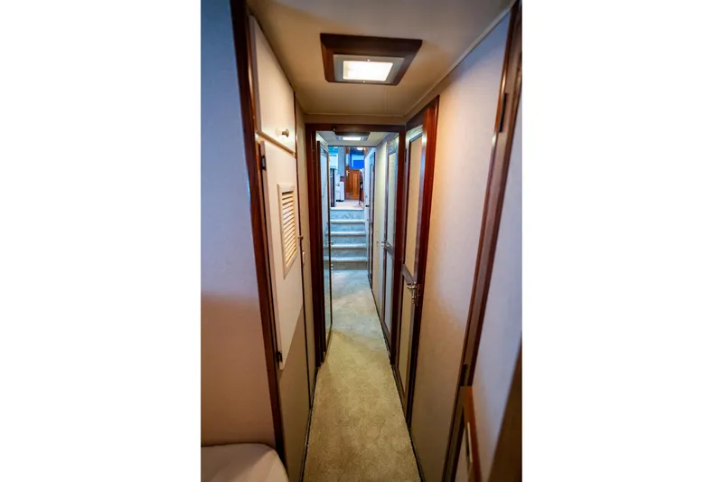 Slide: The Image of Interior hallway of 1984 Hatteras 52 Convertible yacht, featuring wood accents and carpeted flooring. - 75