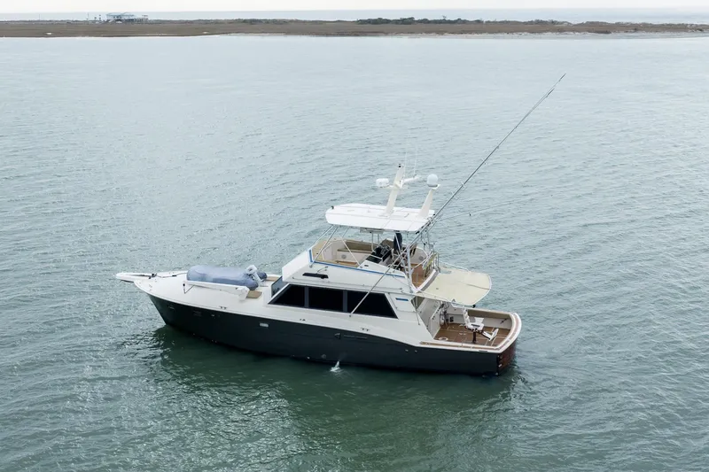 Slide: The Image of 1984 Hatteras 52 Convertible yacht on calm waters, distant shoreline visible. - 9