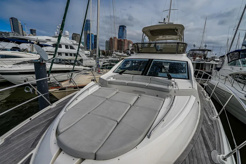 Slide: The Image of 2018 Sea Ray L590 Fly yacht docked in a marina with city skyline backdrop. - 48