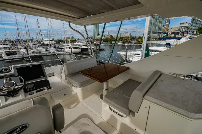 Slide: The Image of 2018 Sea Ray L590 Fly yacht interior with helm, seating, and marina view. - 55