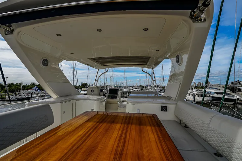 Slide: The Image of 2018 Sea Ray L590 Fly yacht interior with wooden table, docked at marina. - 57