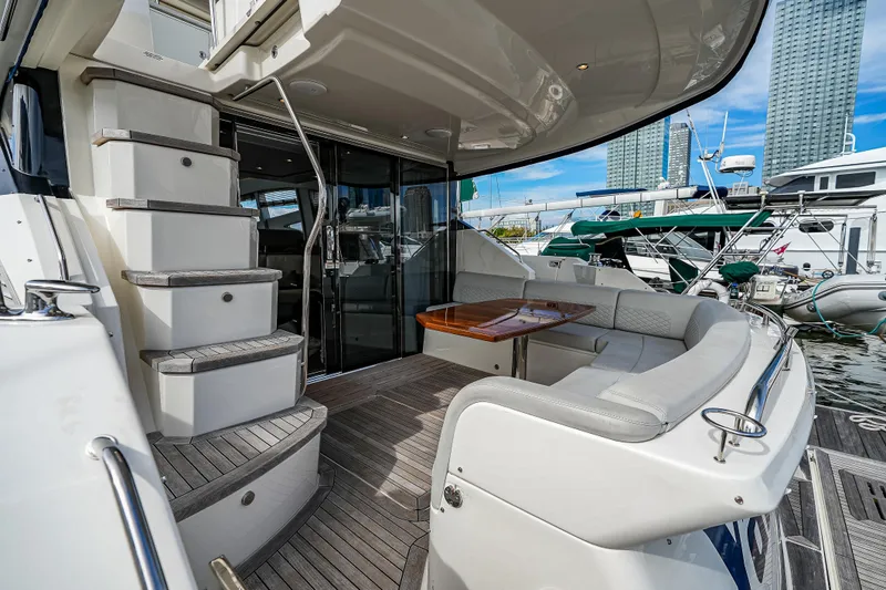 Slide: The Image of 2018 Sea Ray L590 Fly yacht with elegant seating and staircase, docked at a marina. - 9