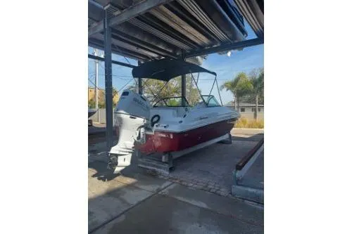 Slide: The Image of 2023 Hurricane SunDeck Sport 188 OB boat in storage, featuring a sleek design and canopy. - 8