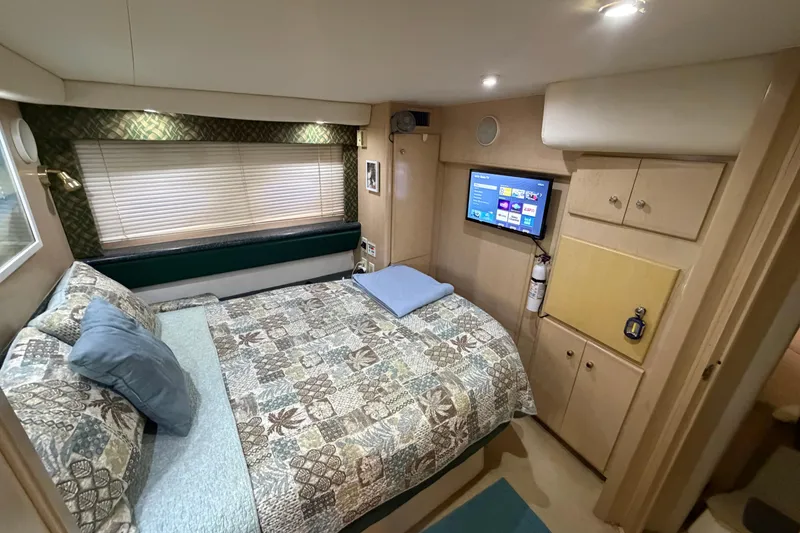 Slide: The Image of 2000 Carver 356 Aft Cabin Motor Yacht bedroom with TV, patterned bedding, and storage cabinets. - 33