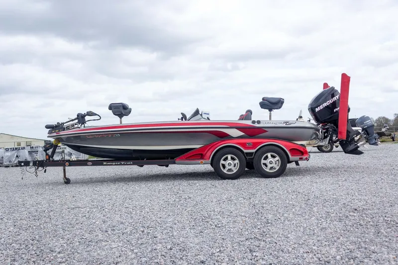 Slide: The Image of 2009 Ranger Z520 Comanche boat on trailer, featuring Mercury engine, parked on gravel. - 12