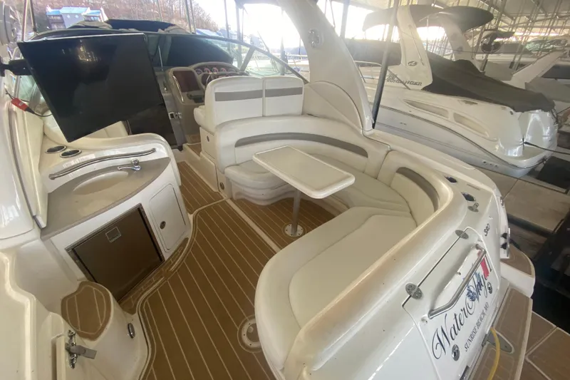 Slide: The Image of 2004 Sea Ray Sundancer 320 interior with seating, table, and kitchenette in a marina setting. - 15